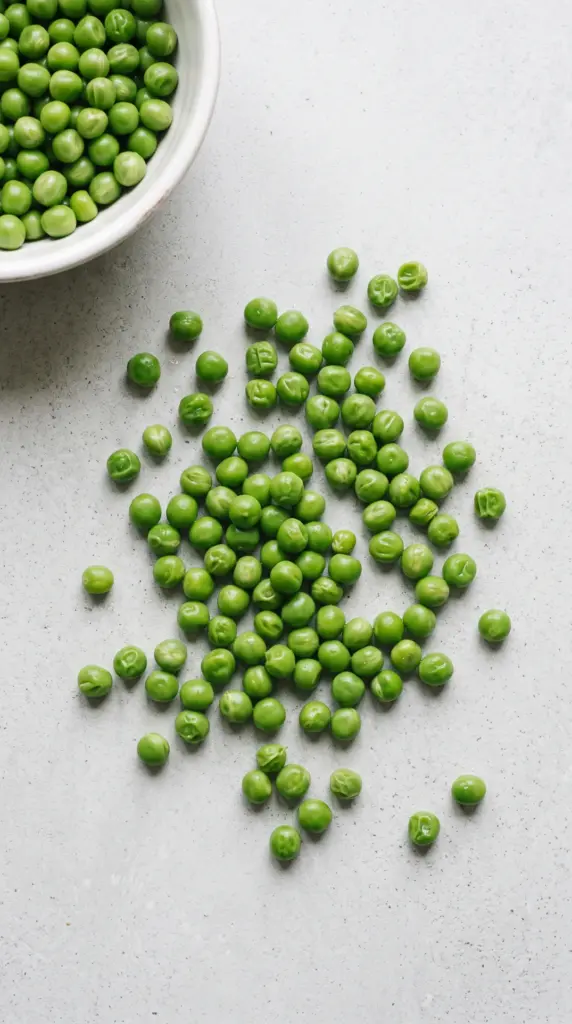 Cooked green peas on a light grey table