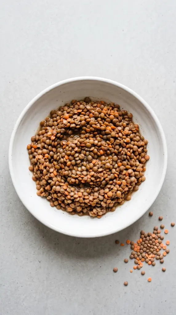 Cooked brown and red lentils on a light grey table